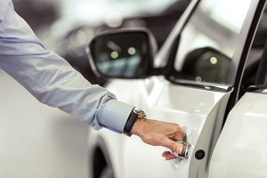 Middle aged businessman in classic shirt is opening a car in a motor show, close-up